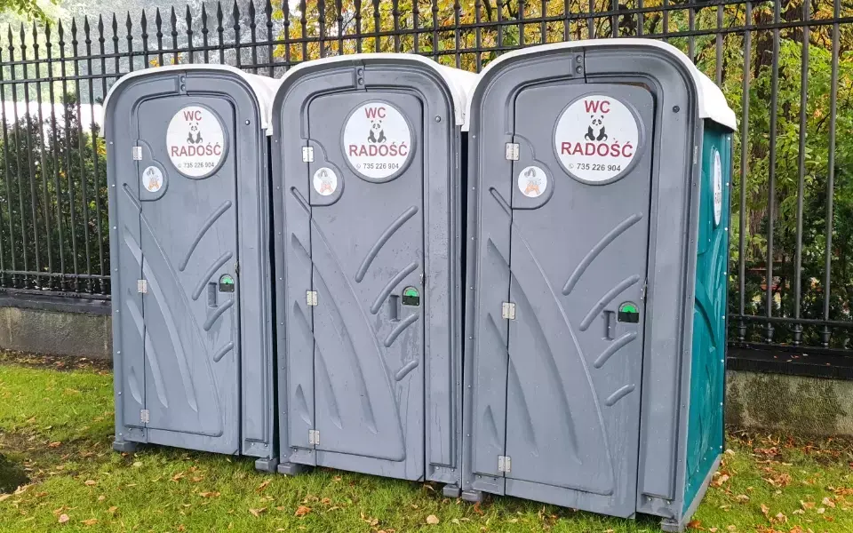 Przenośne toalety ustawione na trawie